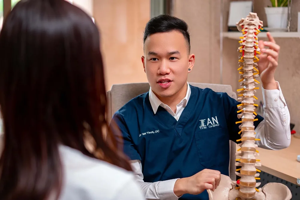 Ian the chiropractor explaining spinal anatomy to a patient during consultation in Cheras KL